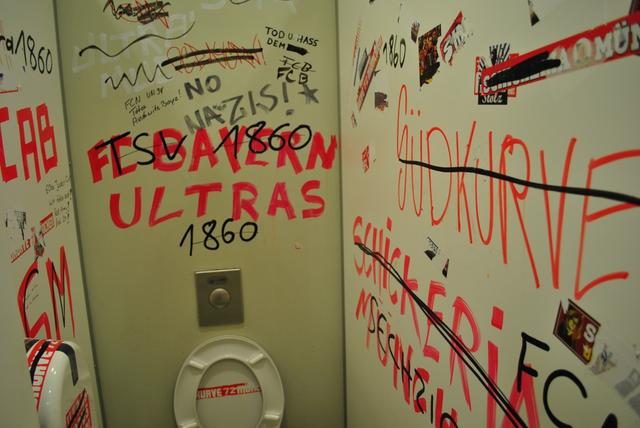 A public bathroom with boisterous comments written on the walls. Most text is not in English, but the phrase