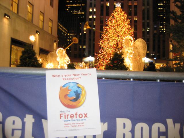 A flyer promoting Firefox hangs on a barricade near the Rockefeller Center Christmas tree in New York City. The flyer reads, 