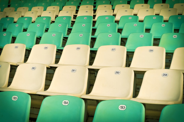 A group of empty stadium seats, with the fronts of the seats facing the camera